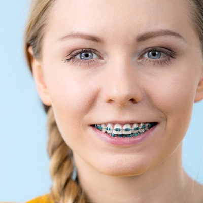Woman smiling with blue braces and ponytail