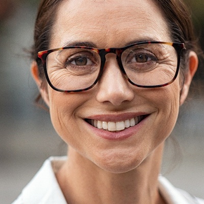 Woman wearing glasses smiling in collared shirt