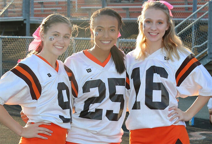 Three girls wearing football jerseys