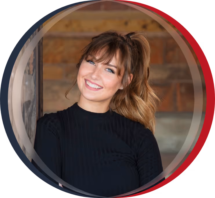 Woman in black coat smiling in front of brick wall