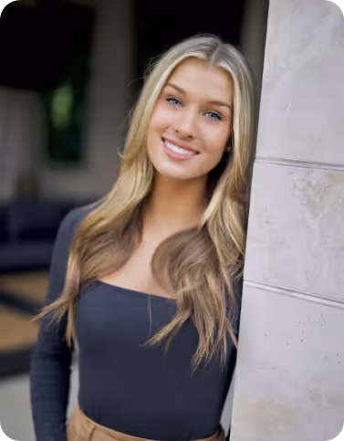 Young woman standing next to wall and smiling