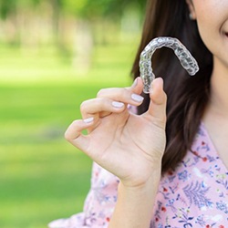 Closeup of woman holding Invisalign in Heath outside
