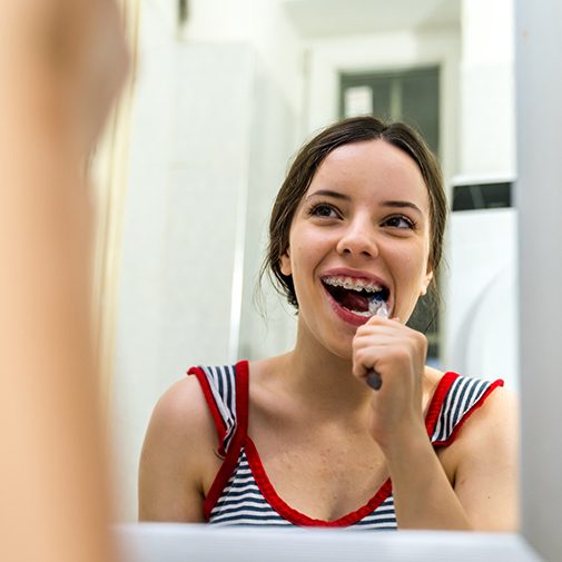 a young woman with braces brushing her teeth