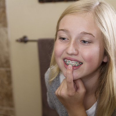 girl looking at braces in the mirror