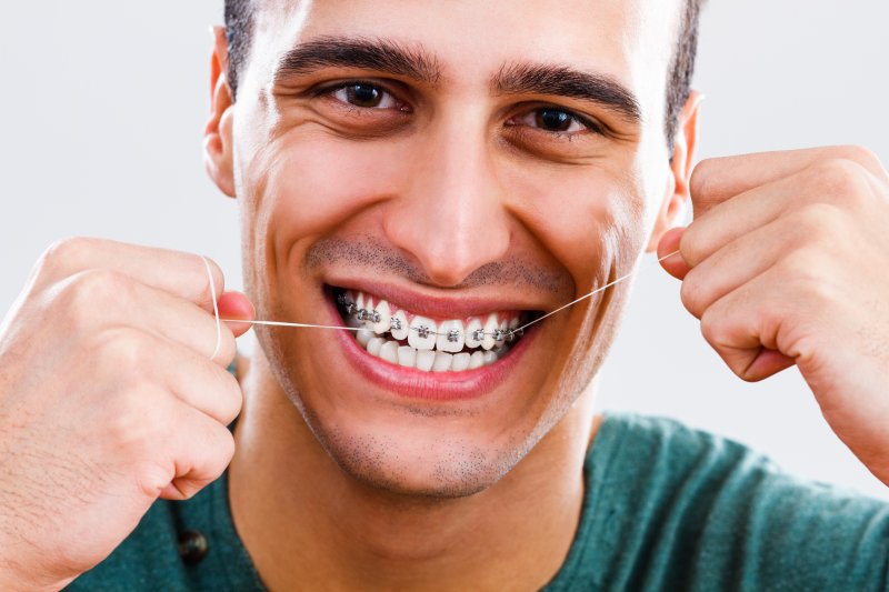 A man smiles broadly while holding his braces.