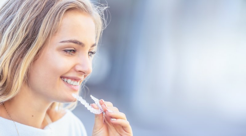 Young attractive adult woman smiling inserting Invisalign in heath.