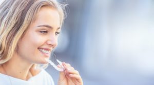 young attractive adult woman smiling inserting Invisalign in heath