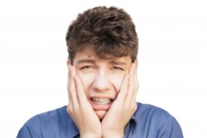 Young man with braces who has pain in his smile