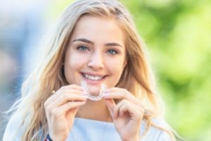 teenage girl smiling holding clear Invisalign in Newark