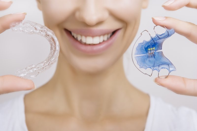 Woman smiling and holding retainers