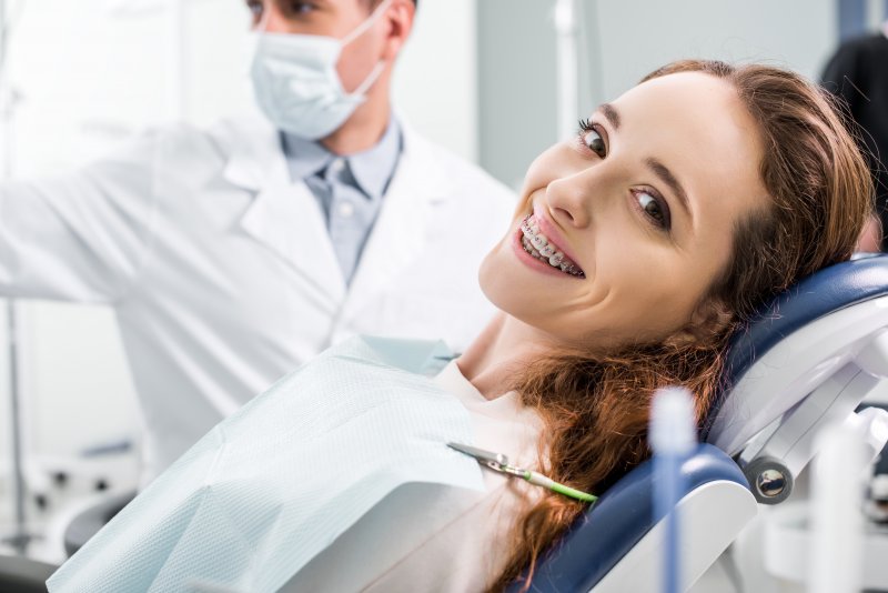 Adult smiling with braces at orthodontist appointment