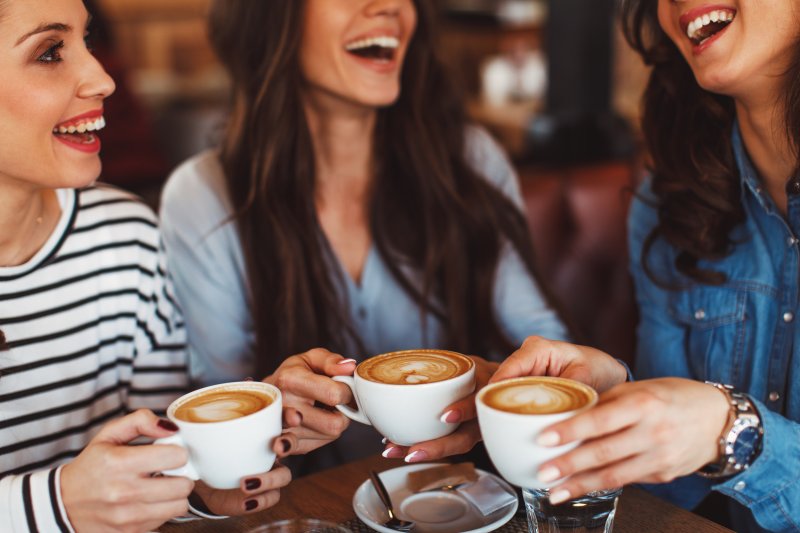 Group of women smiling over cup of coffee