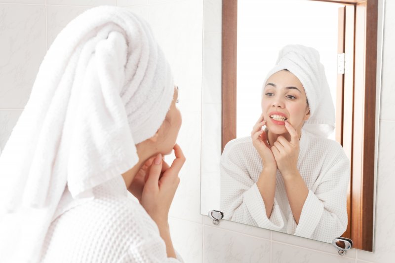 Woman checking her teeth in bathroom mirror
