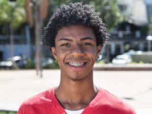 Smiling teen with braces has a braces survival kit