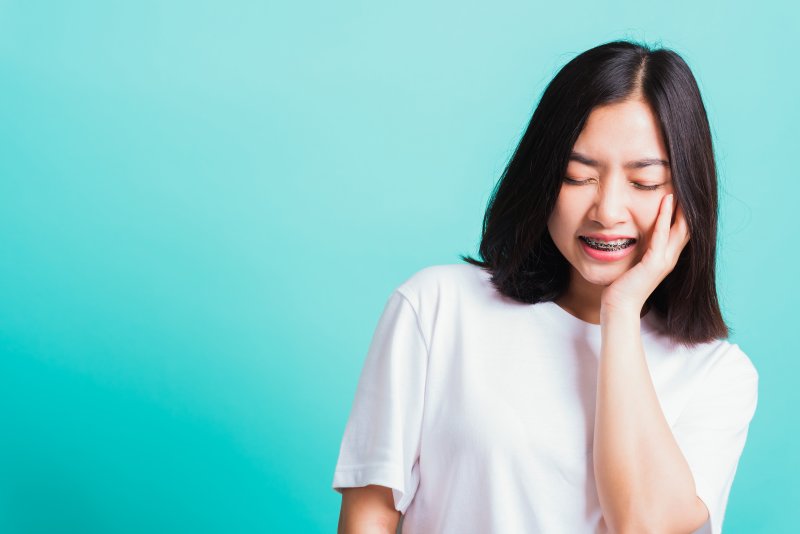 Girl with swollen gums with braces on blue background.