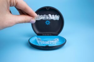 Hand holding Invisalign clear aligners.