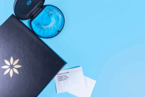 Invisalign aligners, case, and treatment packet on a blue surface